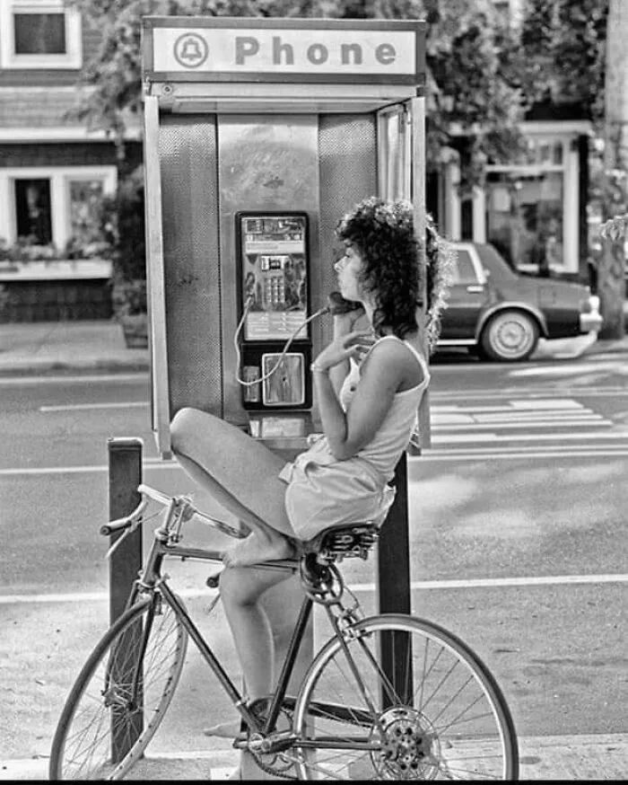 Женщина разговаривает по телефону-автомату, 1980-е.