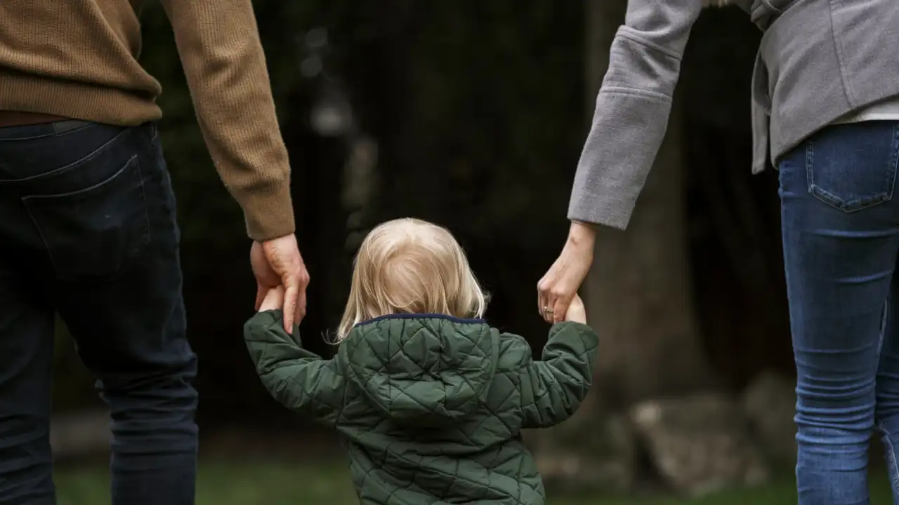 Родители гуляют с ребенком в парке