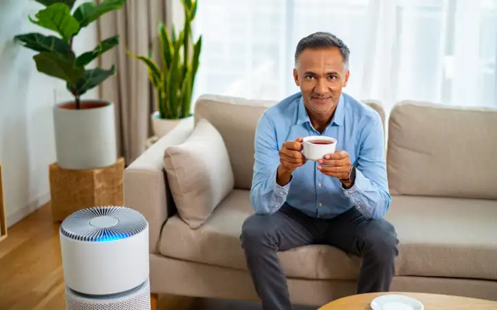 Мужчина в комнате с очистителем воздуха.