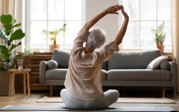 Пожилая женщина тренируется дома.