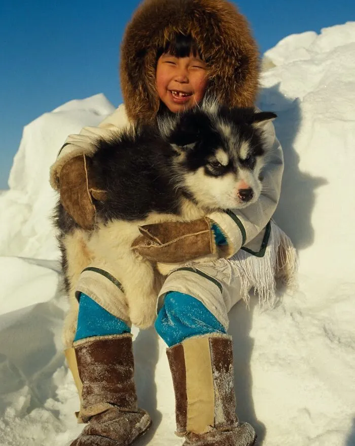 Девочка-инуитка держит на руках щенка.